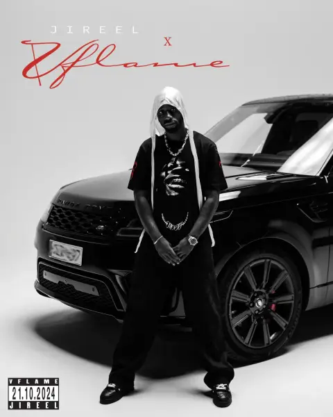 A male artist in a hoodie and chains poses in front of a black SUV.